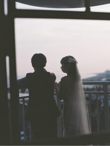 夕景の窓辺で向かい合う新郎新婦