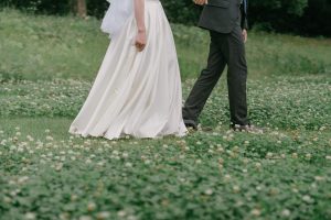 白い花が咲く芝生を歩く新郎新婦の足元