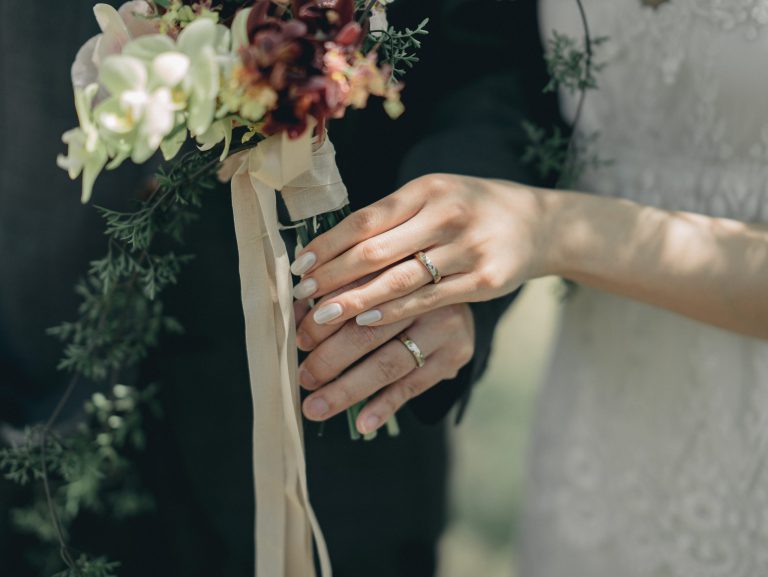 深みのある花色のブーケを持つ新婦の手元と指輪