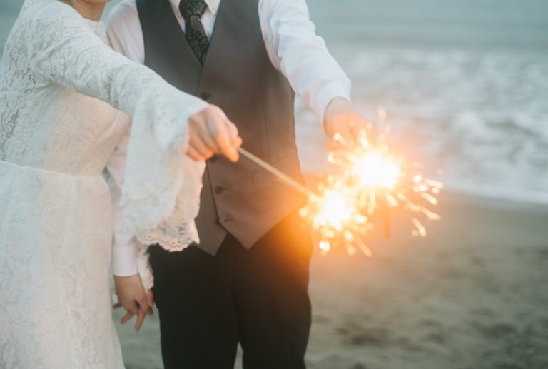 浜辺で線香花火を灯す新郎新婦の手元