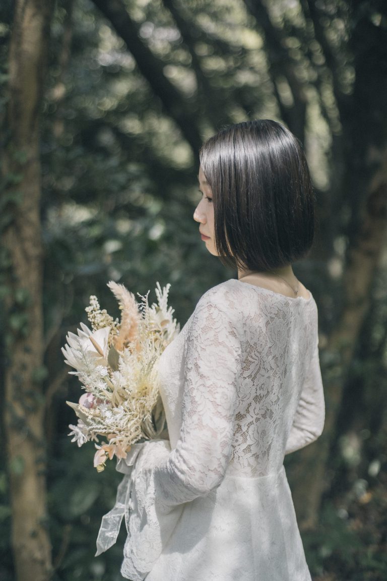 森を背景にドライフラワーのブーケを持つ花嫁の横顔