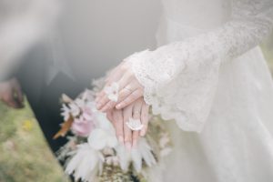 小さな花を手にのせる新婦の指先とレースの袖