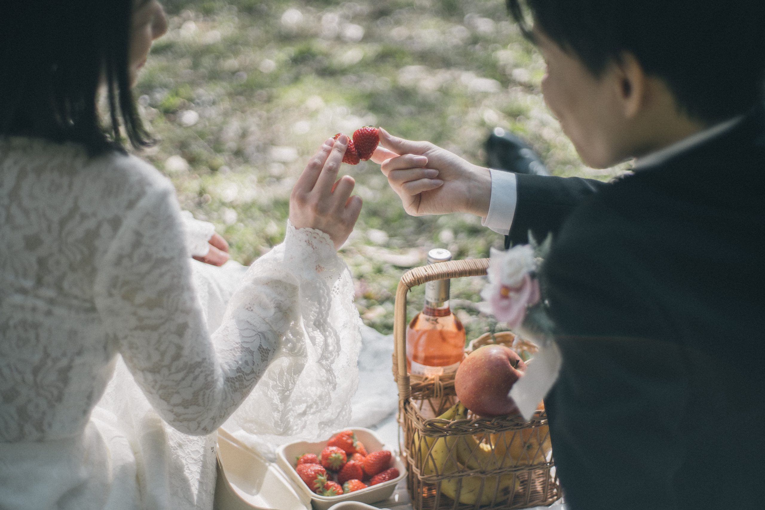 ピクニックの果物を手に取り、ふたりで差し出す手元