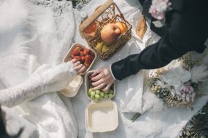 ピクニックの果物に伸ばす新郎新婦の手元