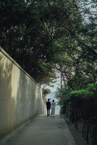 海へ続く小道を手をつないで歩く新郎新婦の後ろ姿