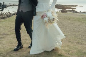 岩場の海岸を歩く花嫁のドレスとブーケ