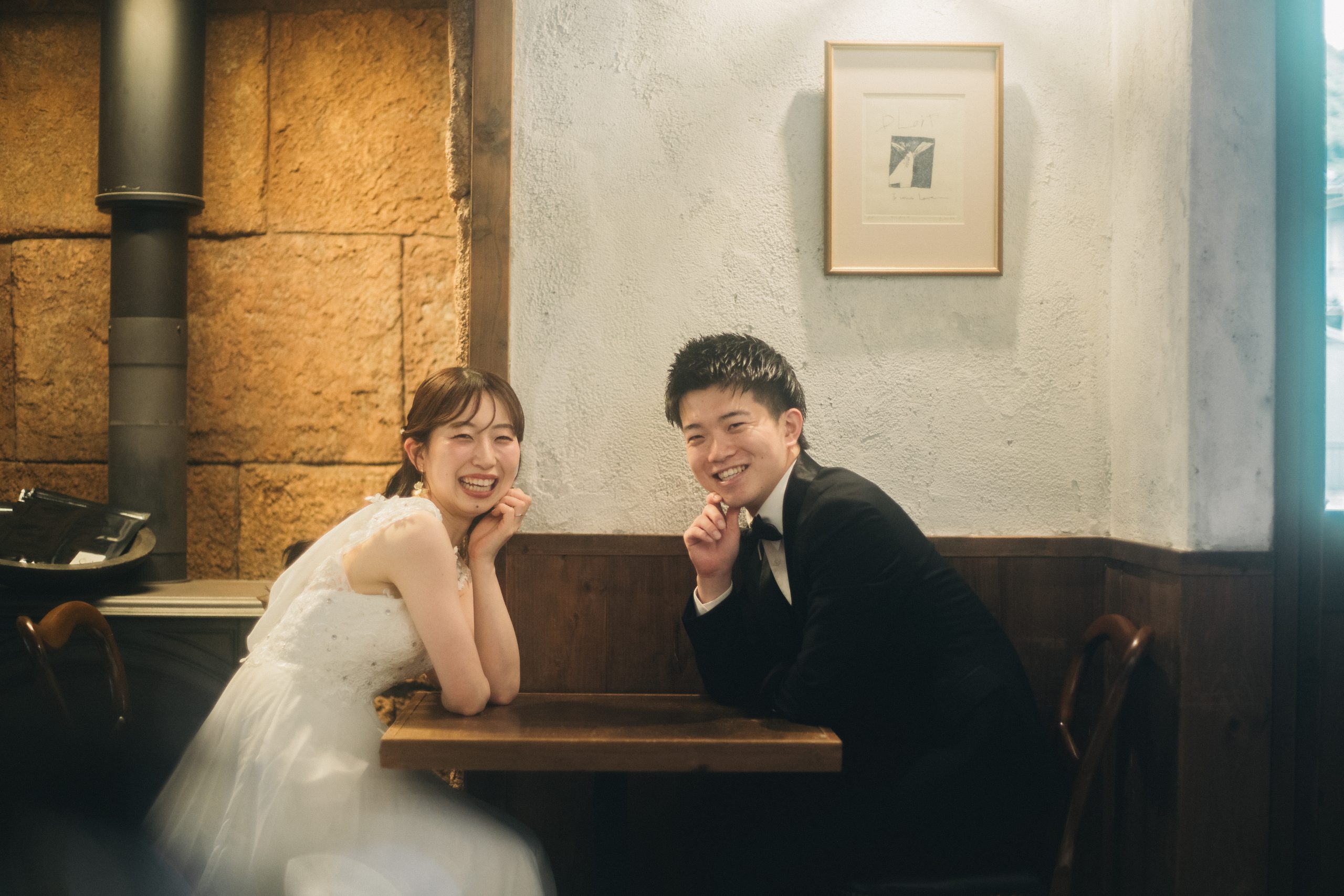 香豆珈琲のテーブル越しに頬杖をつく新郎新婦