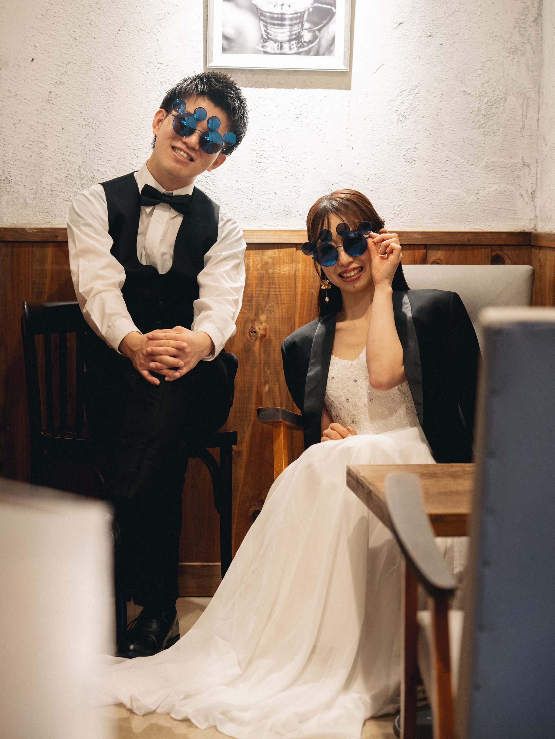 青い丸眼鏡をかけてポーズを取る新郎新婦
