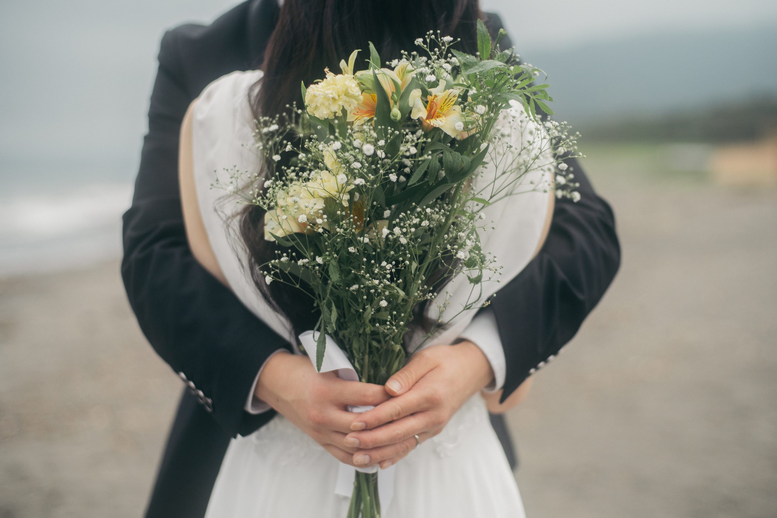 黄色いブーケを囲む新郎新婦の手元