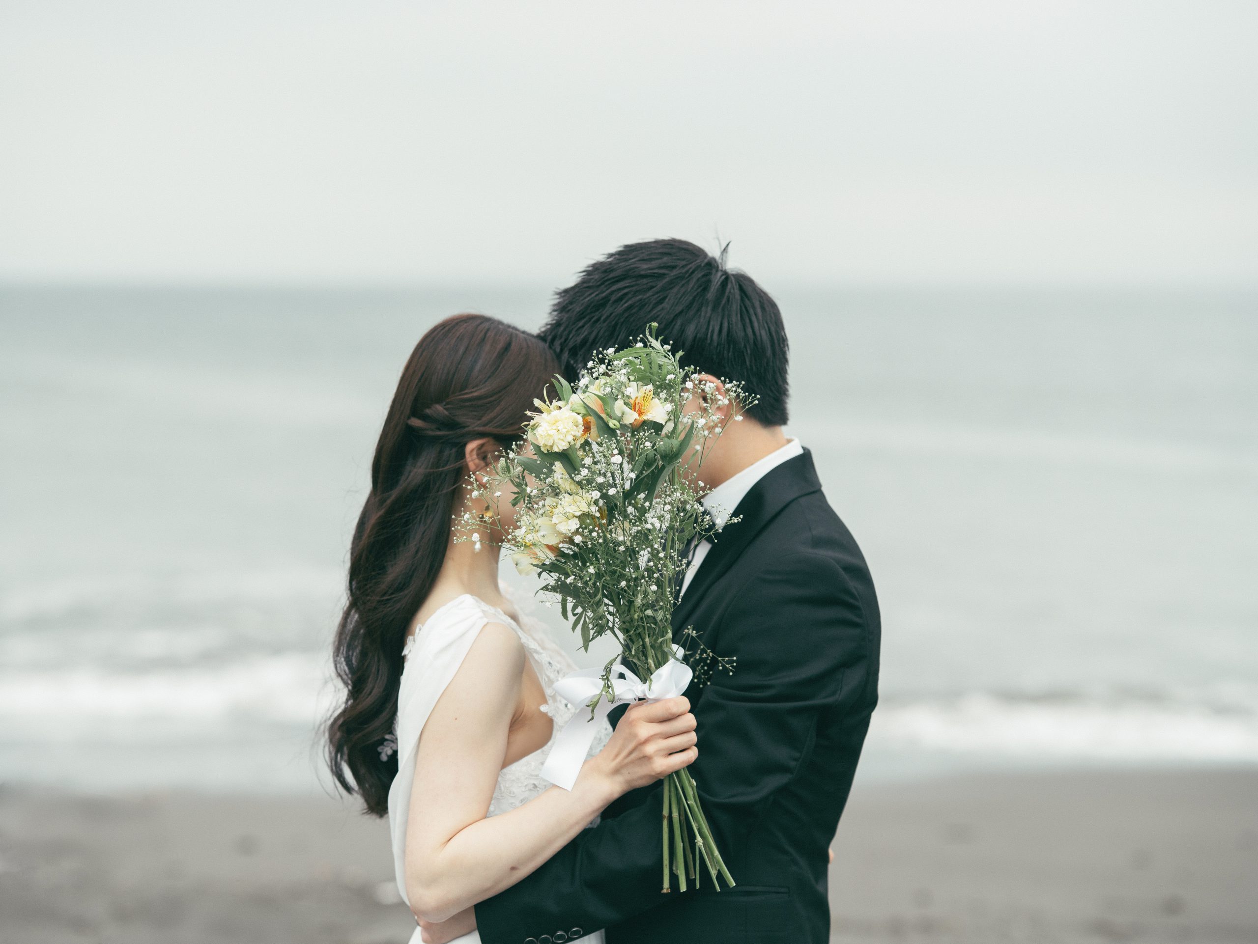 黄色いブーケ越しに顔を寄せる新郎新婦