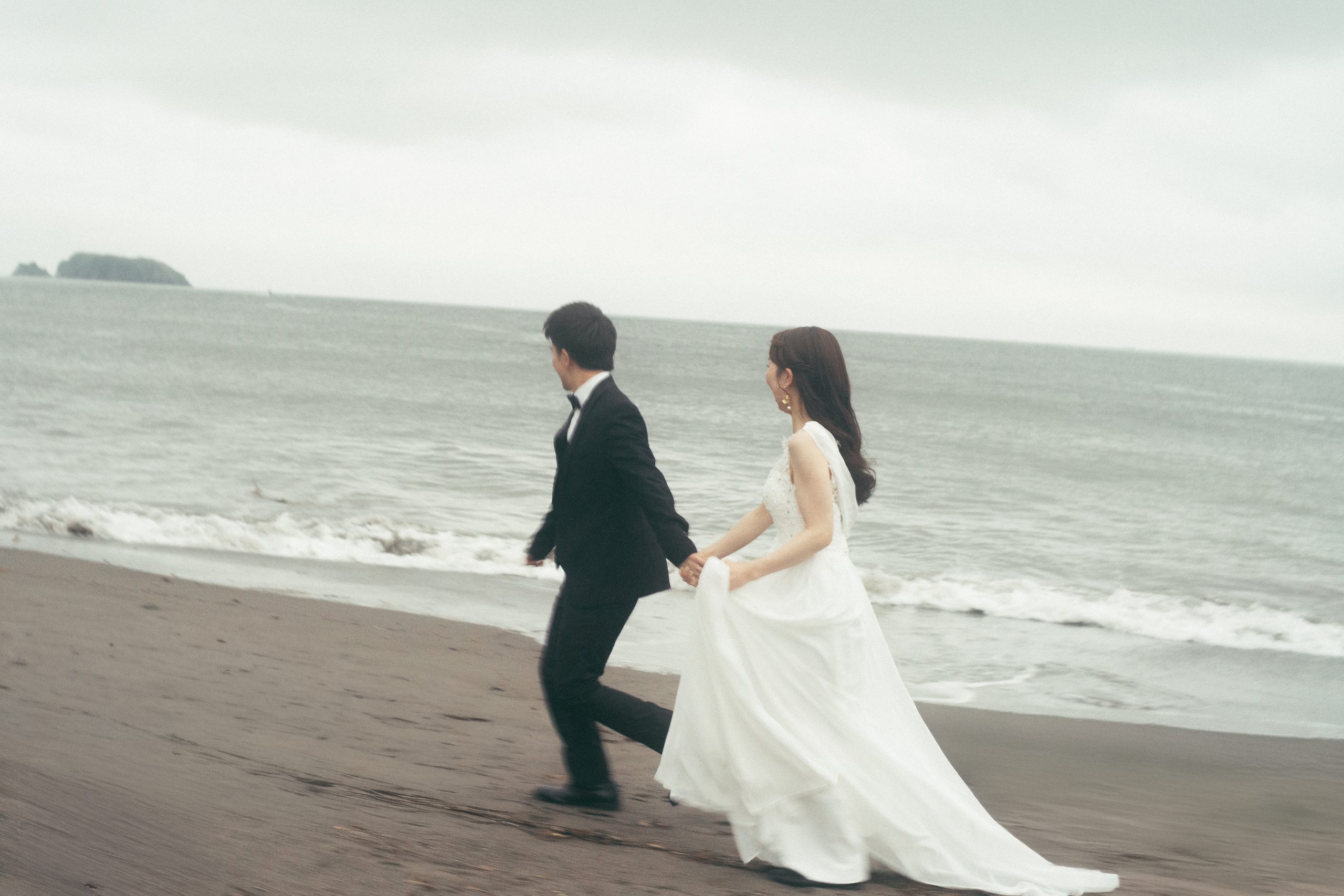 保田中央海岸を手をつないで走る新郎新婦