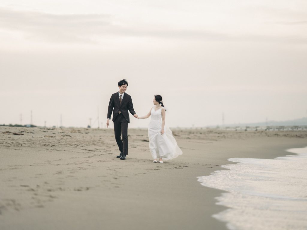 海辺を並んで歩く新郎新婦の後ろ姿